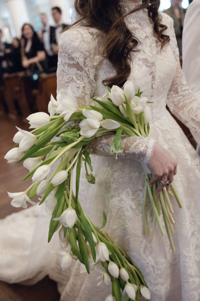 Galveston wedding flowers: Bride's elegant tulip bouquet and laced gown at Sacred Heart.