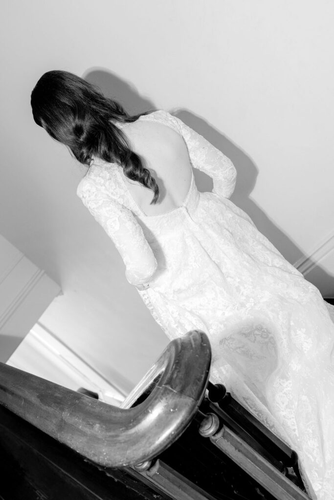 Back view of the bride descending the historic staircase at The Bryan Museum, showcasing the details of her backless wedding dress