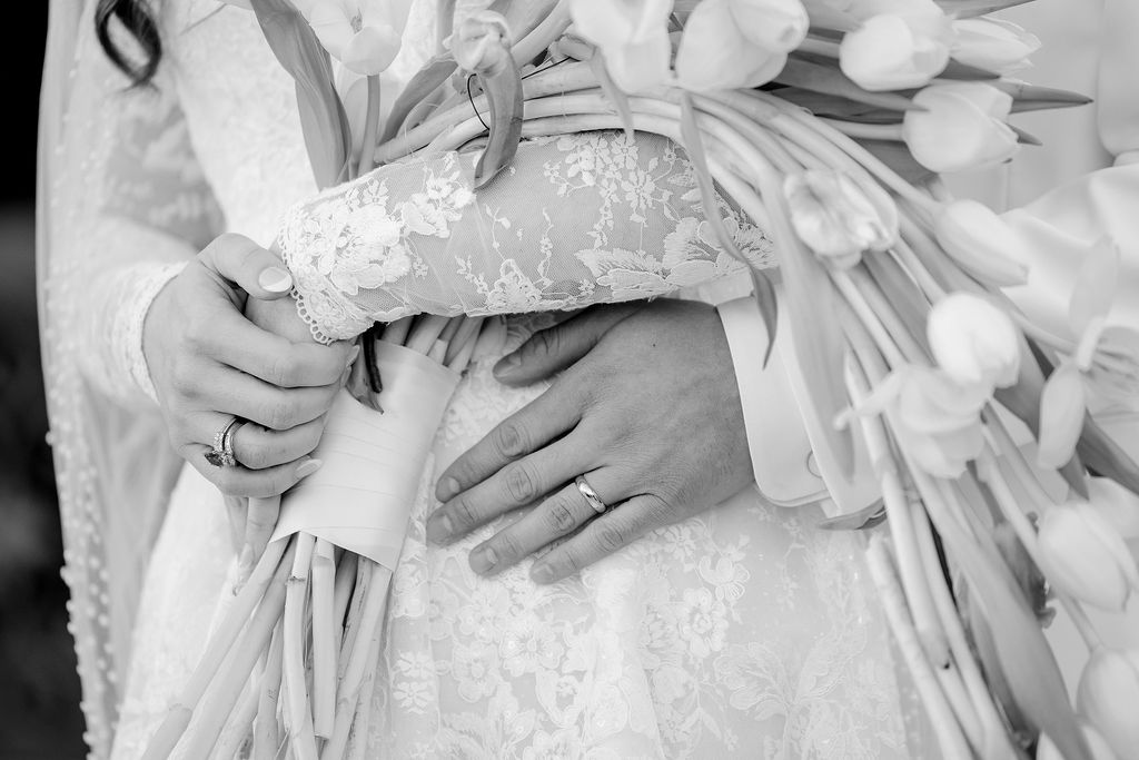 Black and white photo of bride and groom intimately cuddling, captured outside the Sacred Heart Catholic Church, before the Bryan Museum wedding.