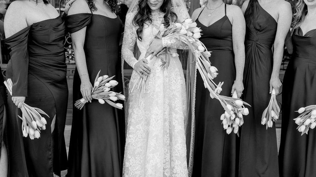 Close-up photo of the Bride with her bridesmaids and their tulip bouquet, captured outside Bryan Museum Conservatory.