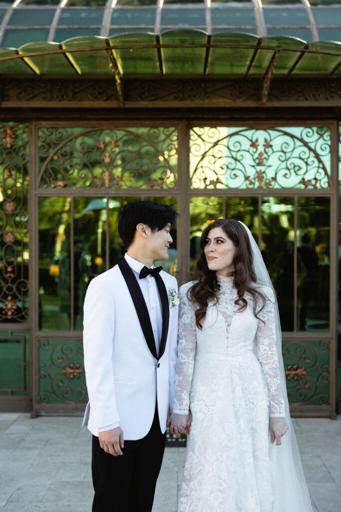 Photo of the bride and groom smiling at each other, captured outside Bryan Museum Conservatory.