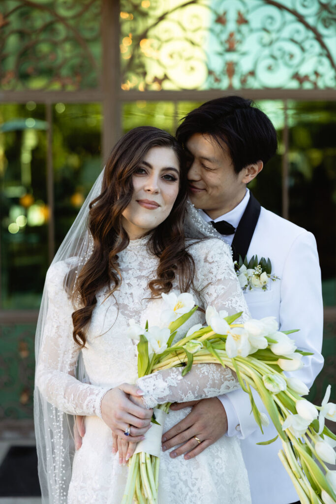 Photo of the groom hugging his bride behind her back, captured outside Bryan Museum Conservatory.