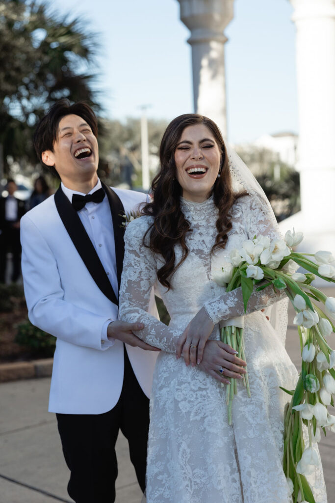 Bride and groom laugh together, captured outside the Sacred Heart Catholic Church, before the Bryan Museum wedding.