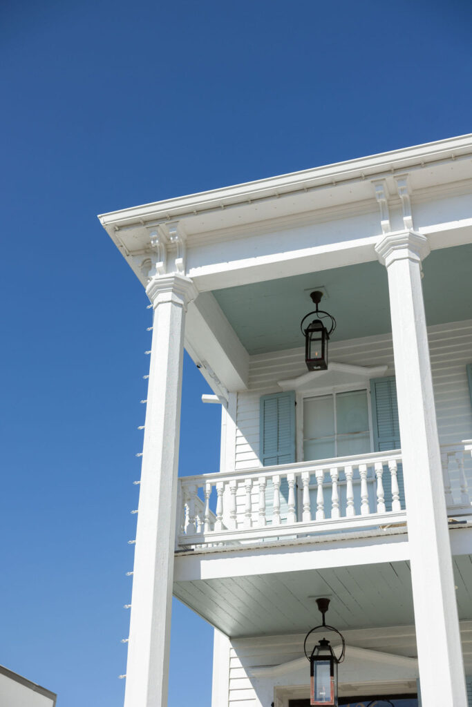 Exterior of the bridal preparation suite for the Bryan Museum wedding in Galveston, Texas, featuring white columns and pastel blue shutters under a clear sky
