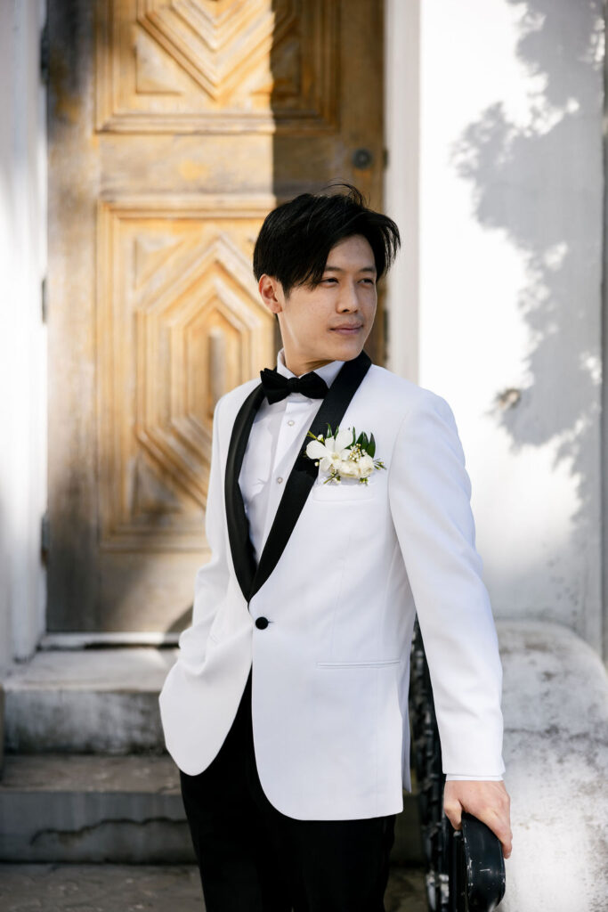 Groom looking into the distance outside Sacred Heart Catholic Church ahead of his Bryan Museum wedding in Galveston, Texas
