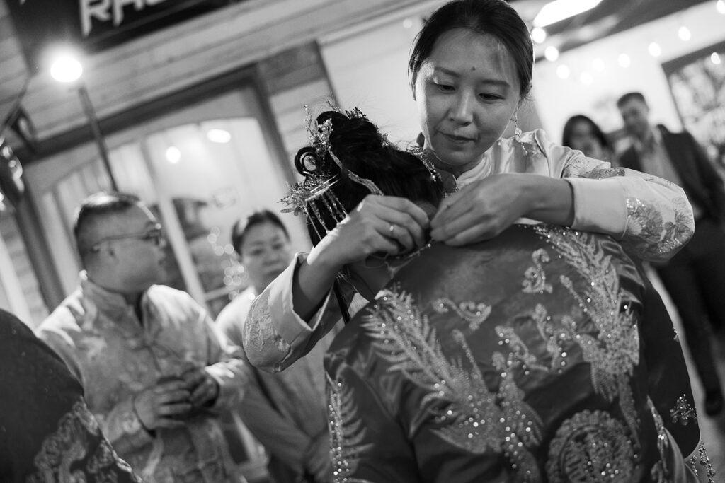 A black and white photo of Jessie hugging Cullen in traditional red and gold outfits during the tea ceremony before their Bryan Museum garden wedding.