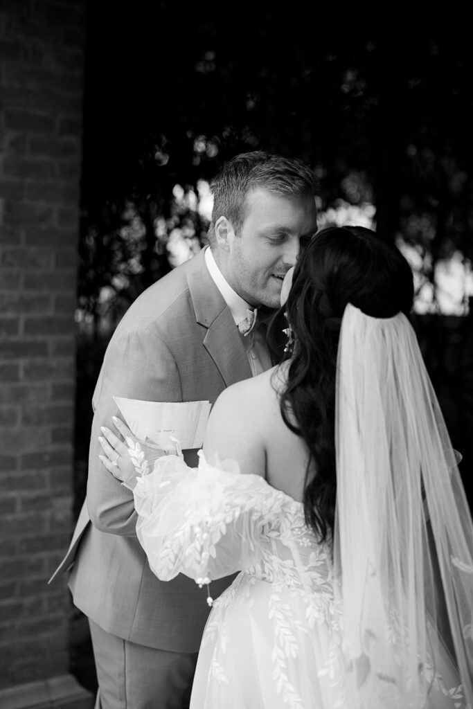 Groom leans to take a kiss at their Bryan Museum garden wedding