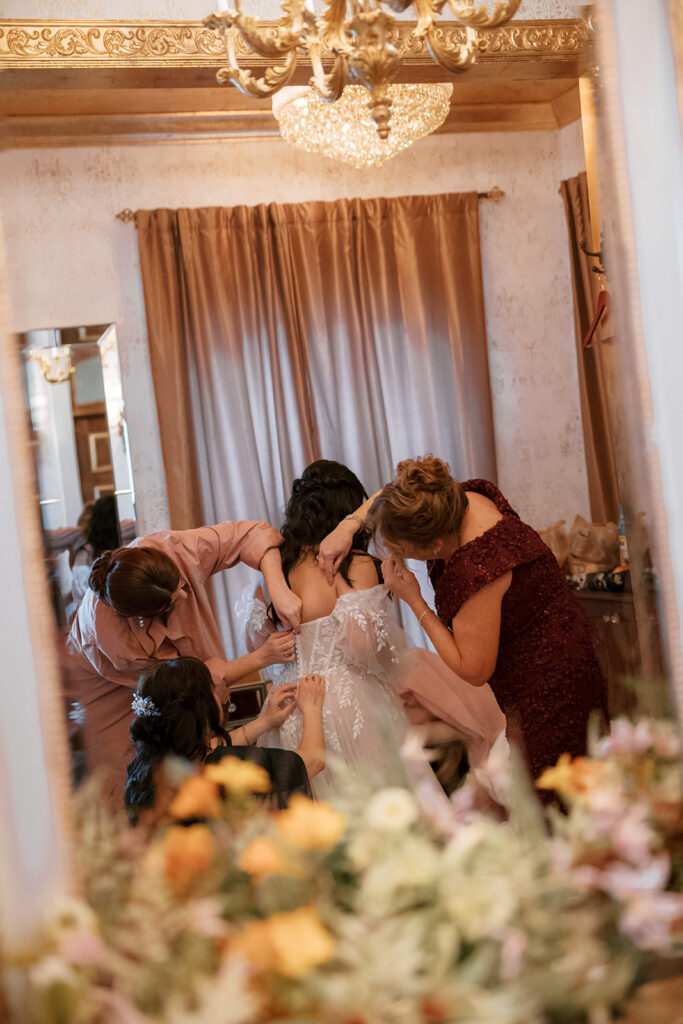 Bridesmaid prepares bride for her Bryan Museum garden wedding.