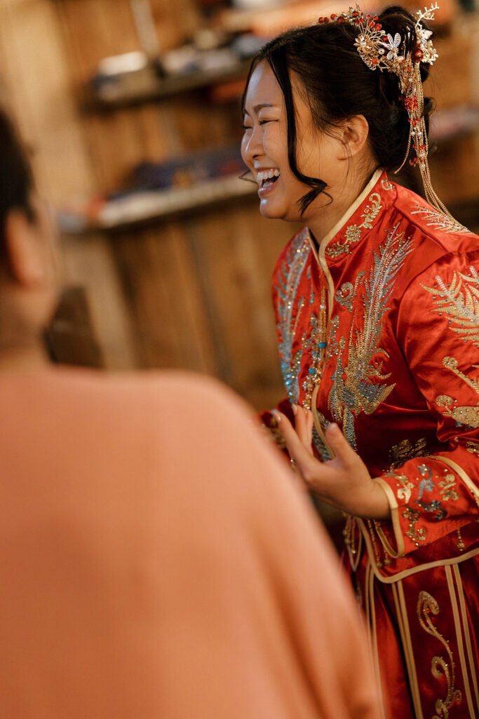 Jessie smiling in her red and gold traditional dress at the tea ceremony before their Bryan Museum garden wedding.