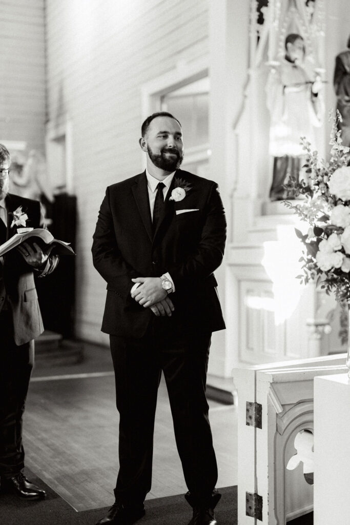 Groom looks at bride across the room for their Real Wedding at Galveston City National Bank Museum