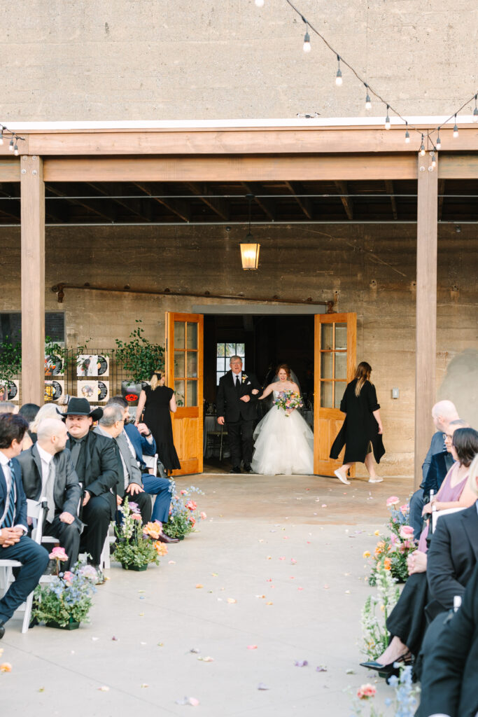 Guests watching as a wedding processional enters at The Artisan.