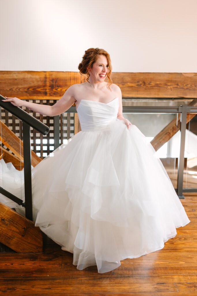 Bride posing on a rustic staircase in her gown at The Artisan wedding.