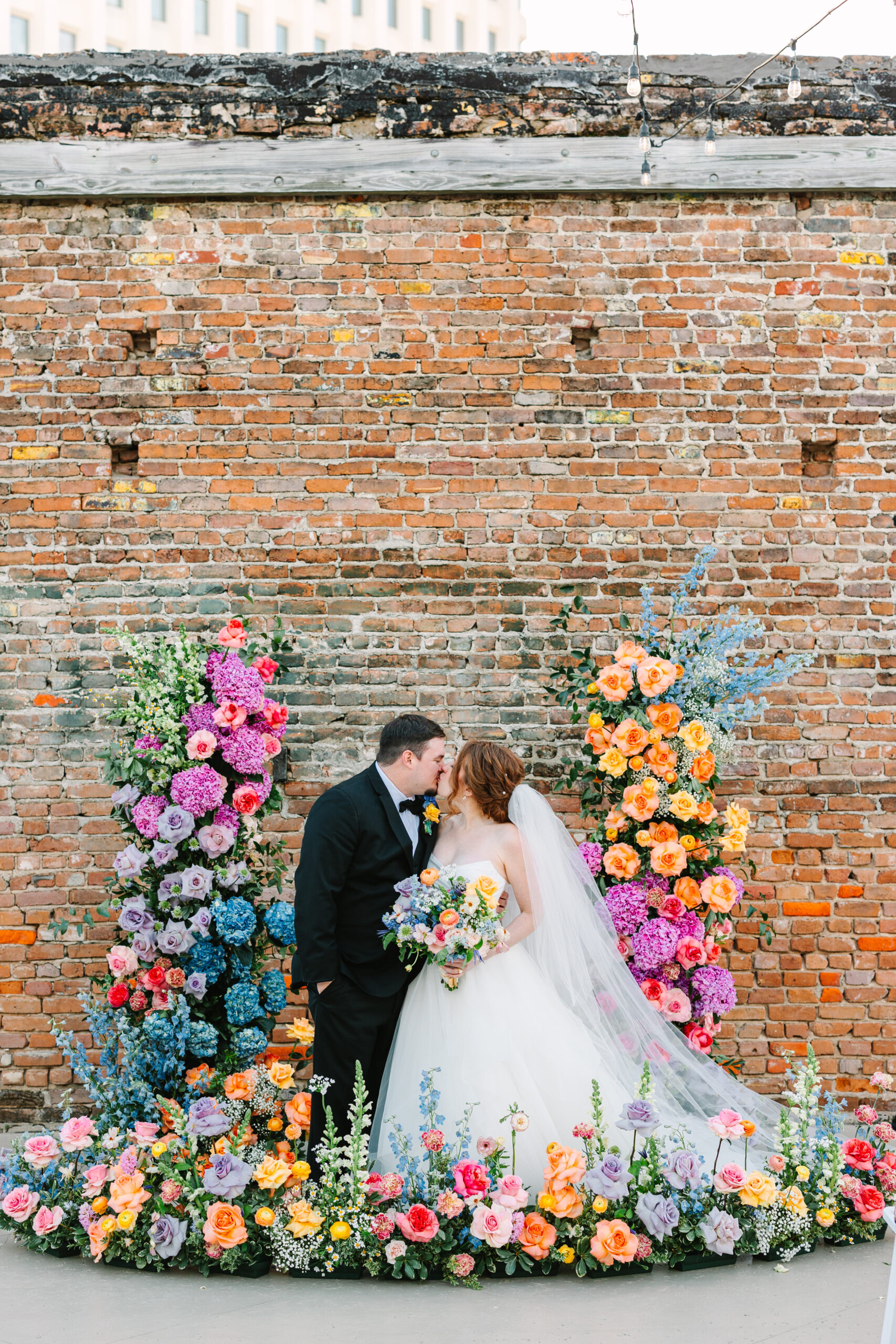 bride and groom surrounded by brightly colored wedding flowers