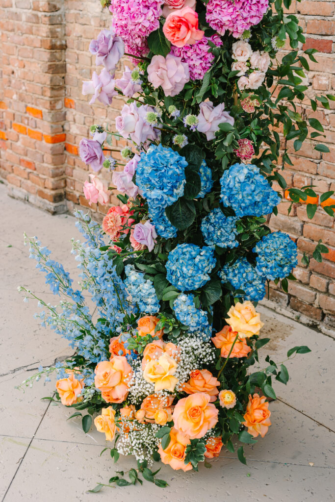 Bright floral arrangement of blue, pink, and orange blooms at The Artisan wedding ceremony.
