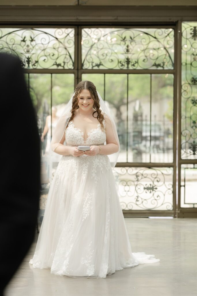 Bride walking toward her first look moment inside The Bryan Museum’s glass conservatory.