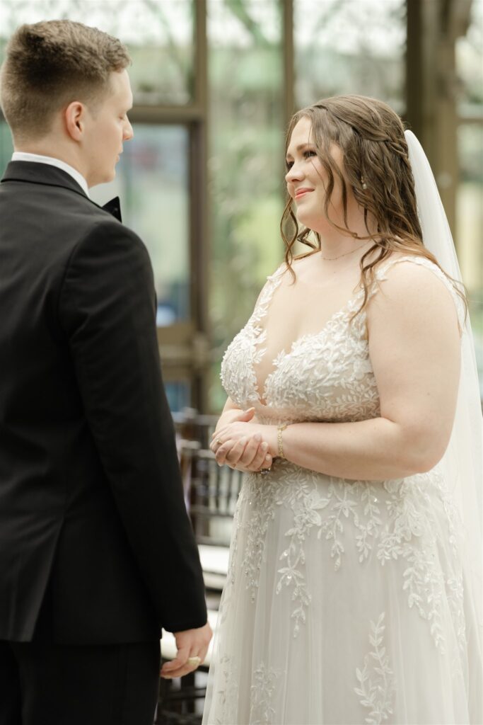 Bride smiles during their first look in the elegant glass conservatory at The Bryan Museum.
