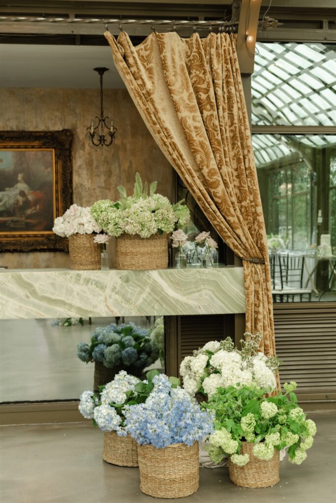 Wedding ceremony décor at The Bryan Museum with gold drapery and lush floral arrangements.