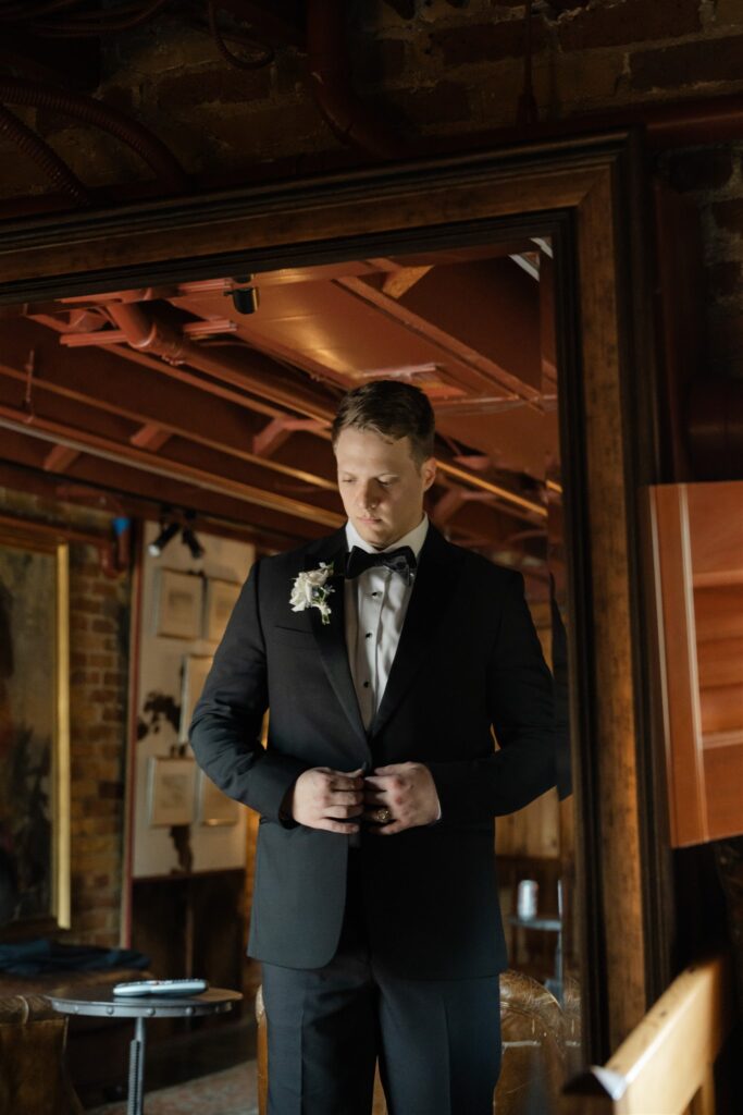 Groom adjusting his suit jacket inside The Bryan Museum before the wedding ceremony.