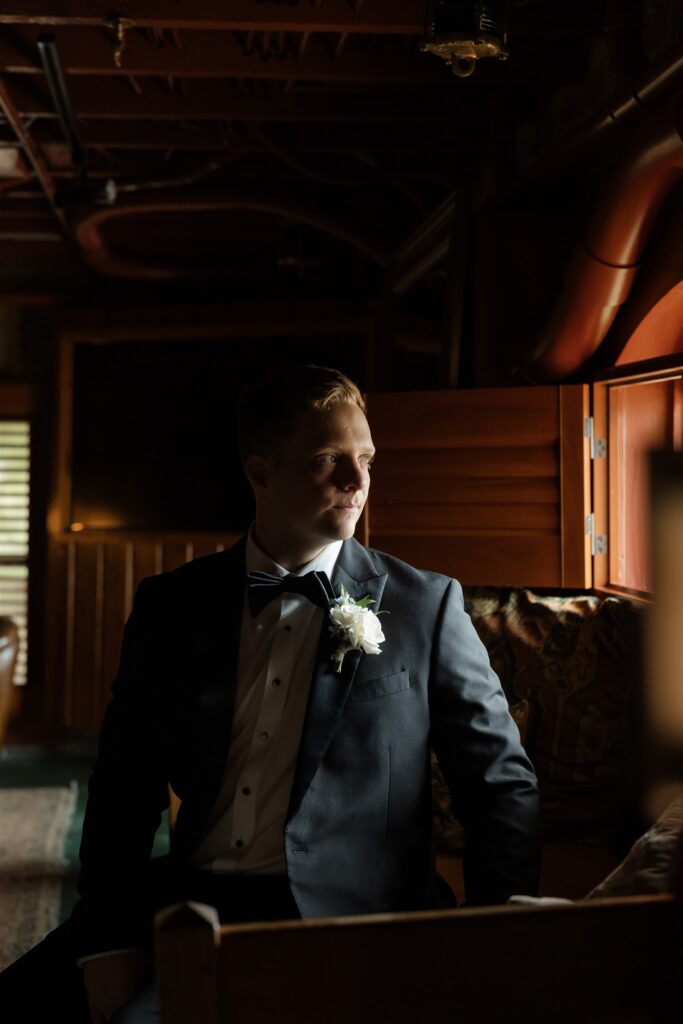 Groom in a black tuxedo waiting inside The Bryan Museum on wedding day.