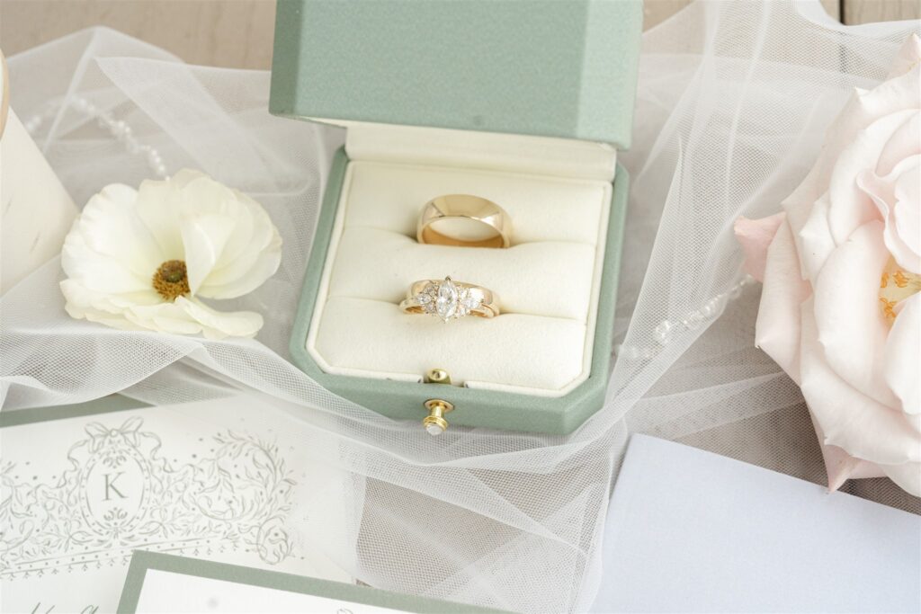 Close-up of wedding rings and invitation suite with soft blush and ivory florals at a Bryan Museum wedding.