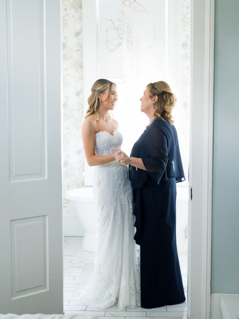 Mother helping bride with her gown during morning preparations for a fall wedding at The Bryan Museum.