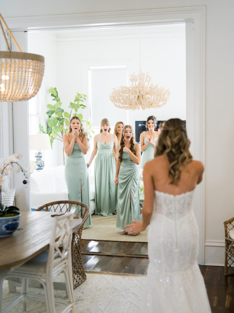Bride showing her gown to her bridesmaids during a heartfelt first look at a fall wedding at The Bryan Museum.