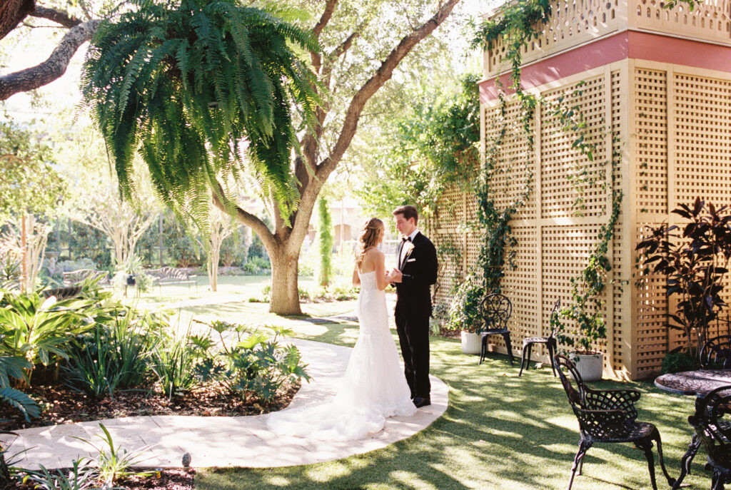 Bride and groom shares first look outdoors beneath trees during romantic fall wedding portraits at The Bryan Museum.