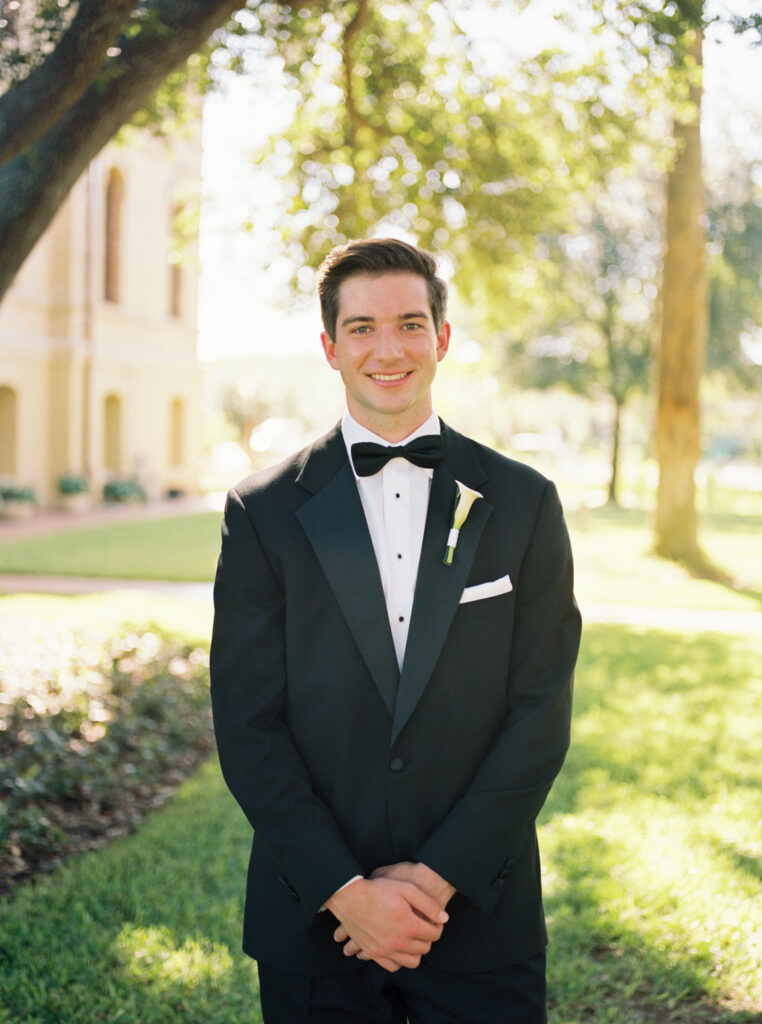 Groom smiling outdoors beneath trees during romantic fall wedding portraits at The Bryan Museum.
