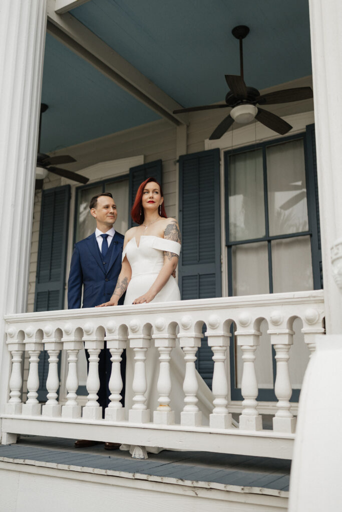 Bride and groom embracing on the veranda during their Carr Mansion wedding in Galveston, Texas.