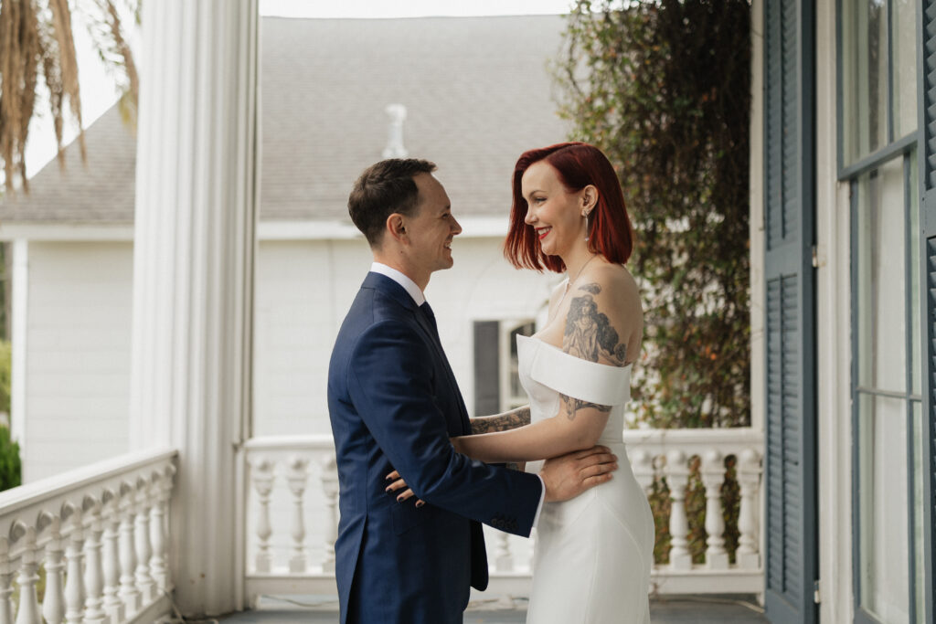 Romantic first look at Carr Mansion wedding venue featuring bride and groom on the porch.