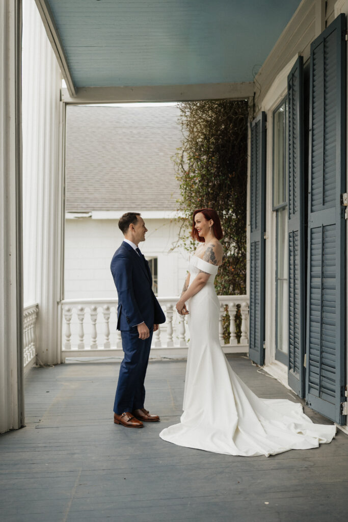 Bride and groom sharing a first look on the porch of Carr Mansion wedding venue.