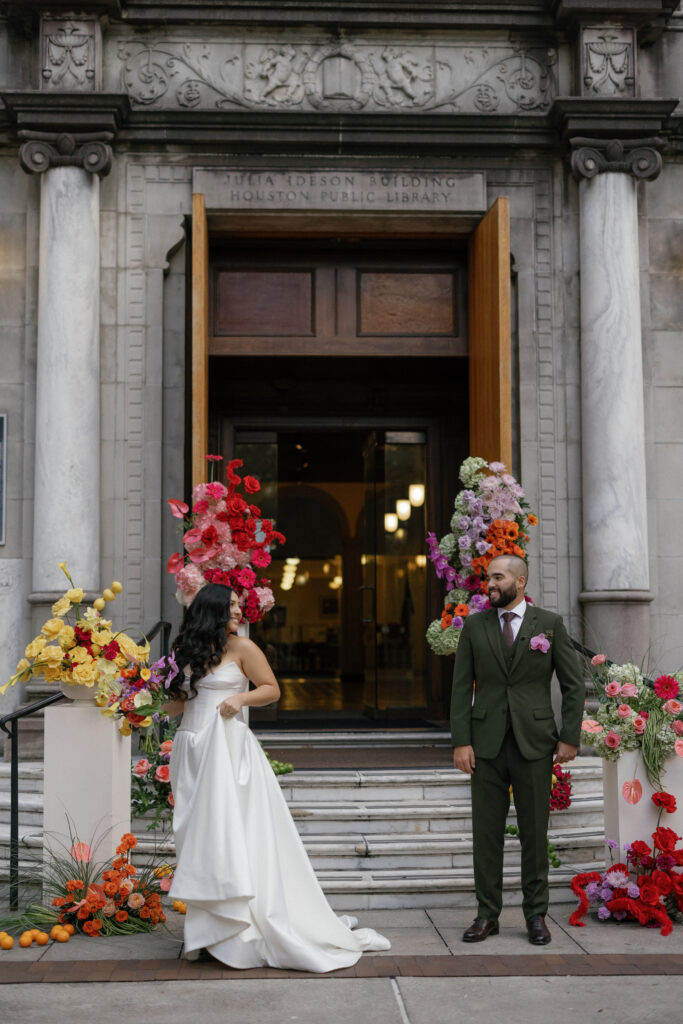 Bride and groom portrait in front of the floral ceremony entrance at the Julia Ideson Library wedding.