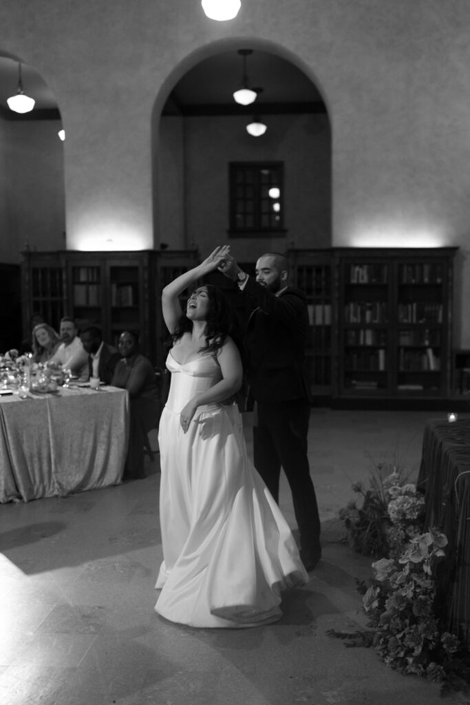 Black-and-white photo of Jessica and Michael dancing together with atwirl of dress during their first dance.